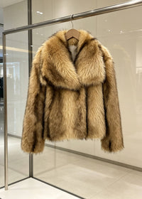 Honey camel brown short faux fur coat with oversized lapel hanging in showroom