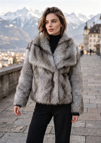 Front view of model wearing frosted silver gray short faux fur coat against mountain backdrop