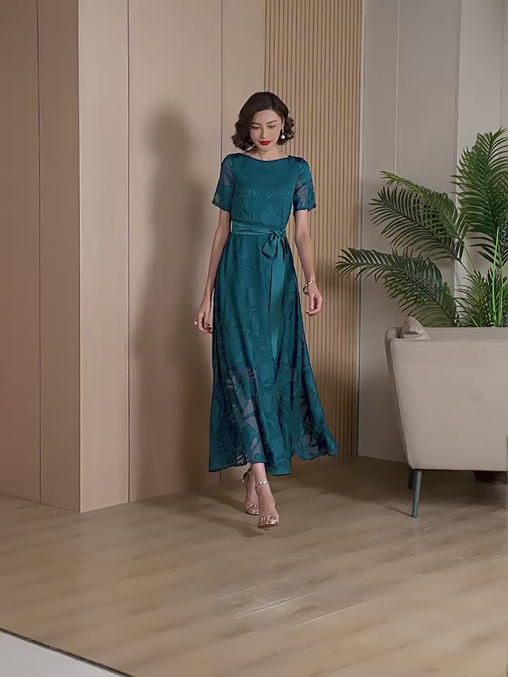 Video showcasing the movement and shimmer of the Elegant Green Floral Jacquard Maxi Dress as a model walks and poses.